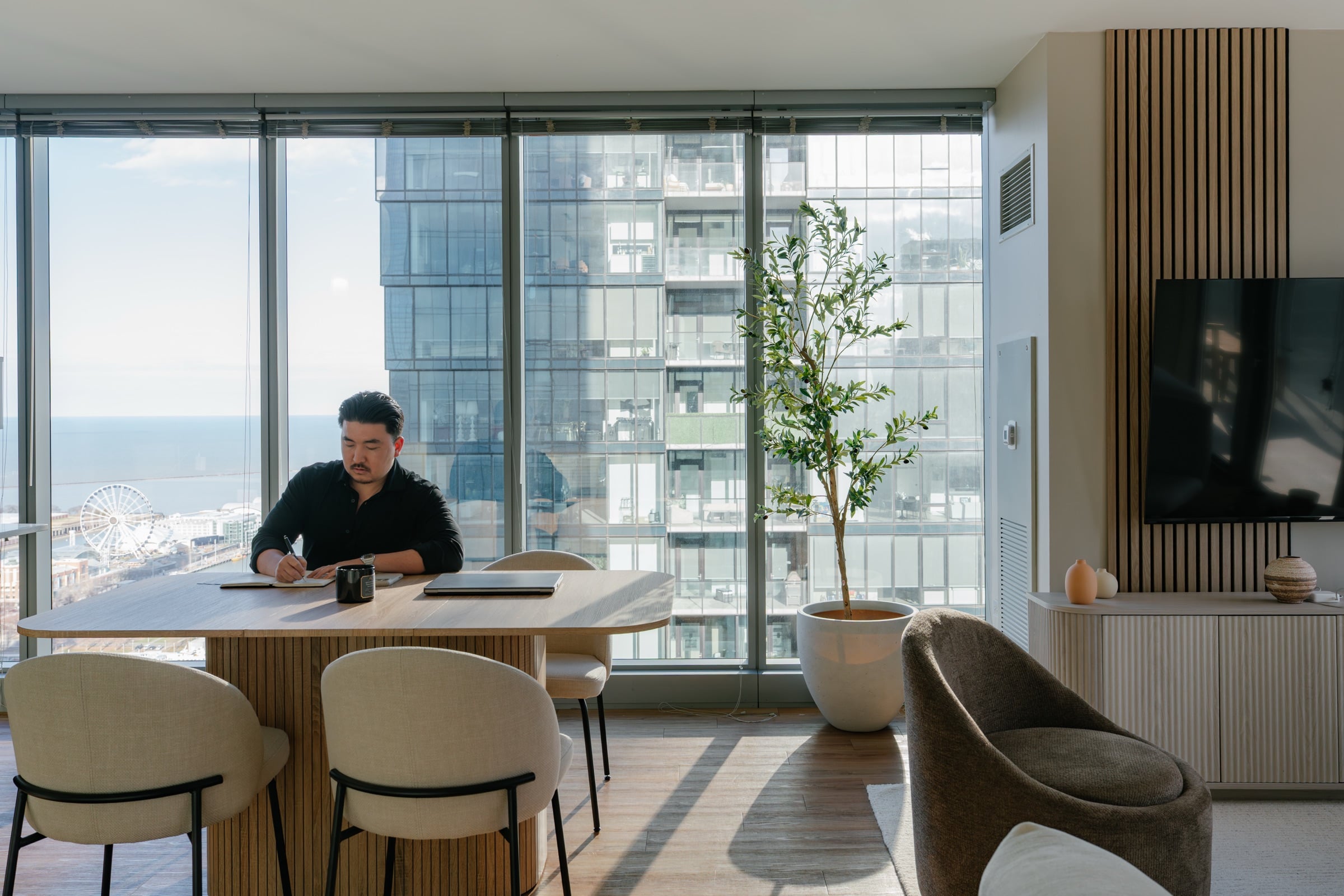 Drew Johnson working at the dining table of a World Class residence, the Chicago lakefront beyond