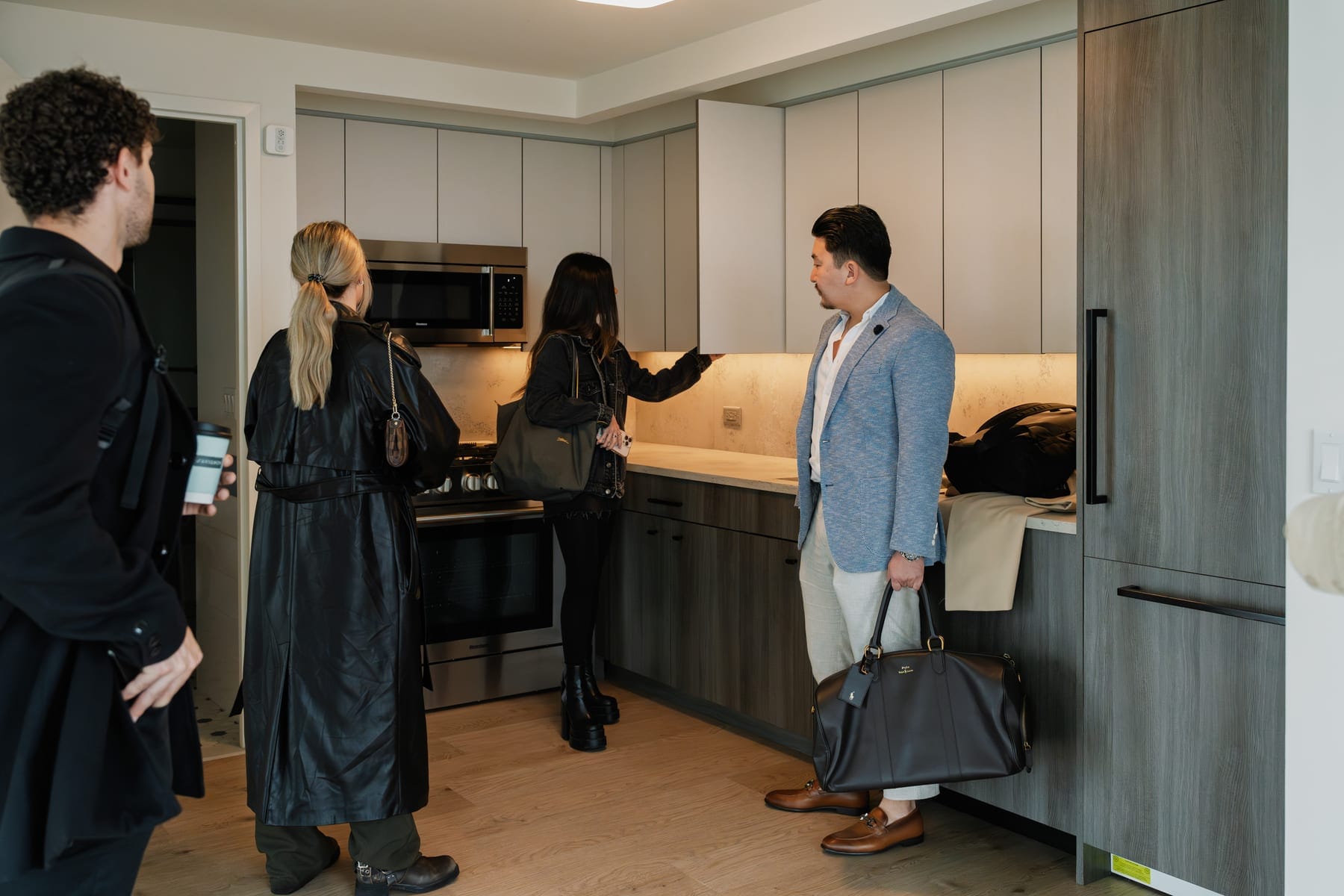 A group arriving together with luggage, being shown the kitchen of a World Class residence