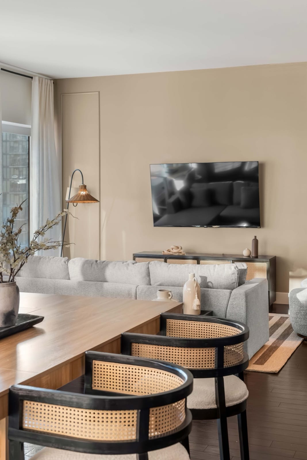 A World Class living room still in order years in, with a pale sofa, a low table and the city through full-height windows