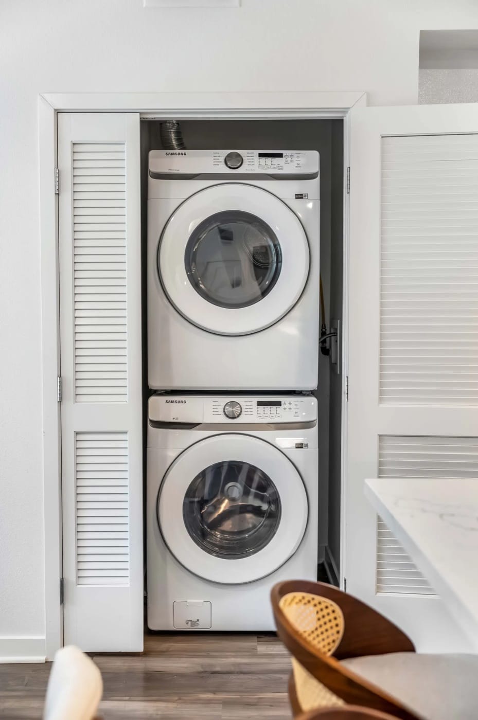 A stacked washer and dryer behind louvred doors inside a World Class residence
