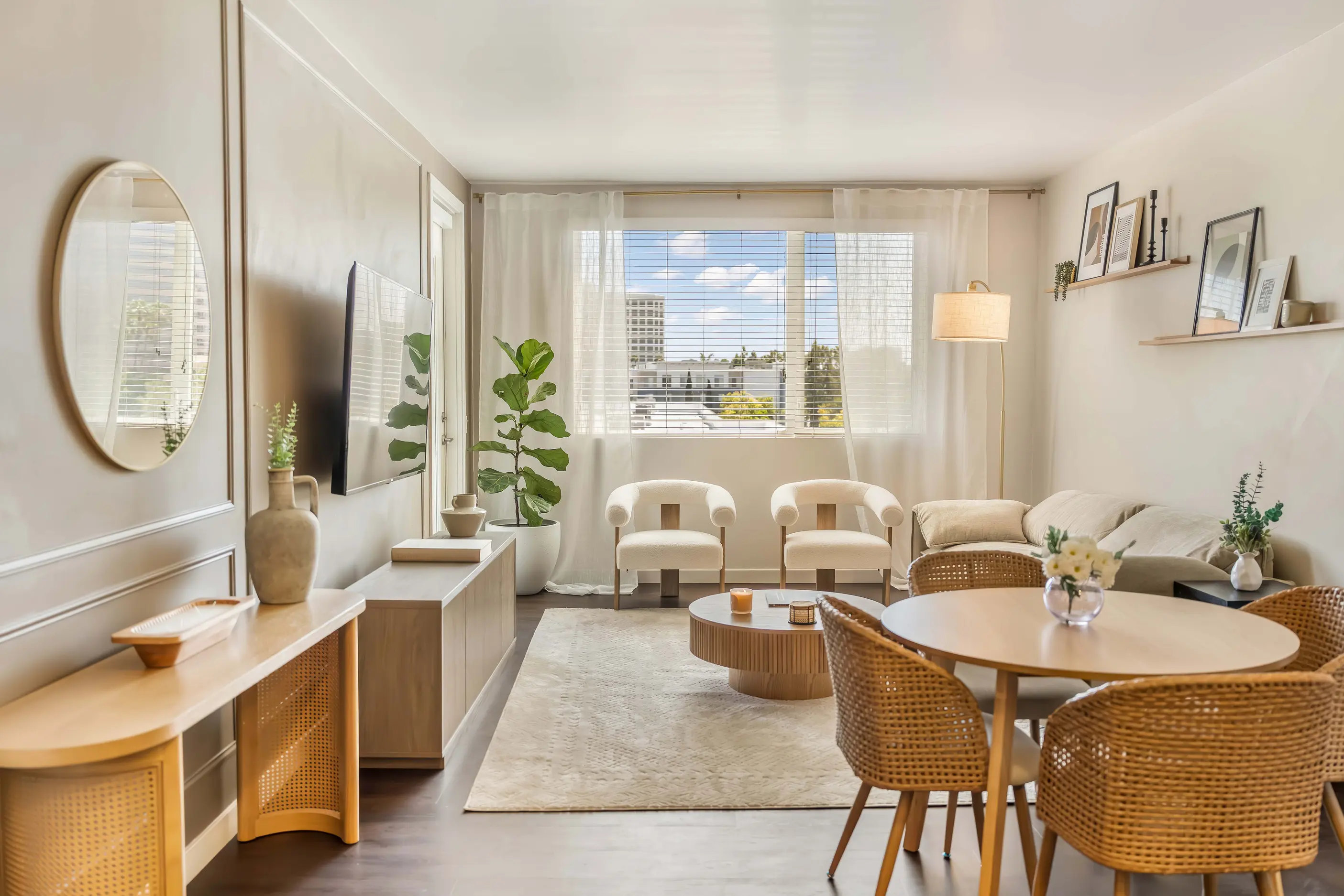 Living room and dining area with pale seating, woven chairs and curtain framed windows at The Manchester by World Class® in Irvine